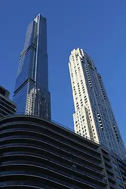 The Central Park Tower (the glass building at left) and 220 Central Park South (the stone building at right), as seen from Seventh Avenue. In the foreground is a shorter glass building at 200 Central Park South.