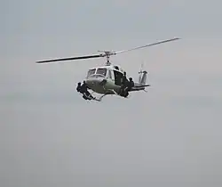 A helicopter flying with four special police troops standing on its landing skids