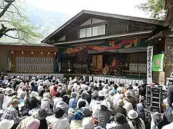 Outdoor stage with actors in traditional Japanese costumes.