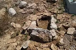 A small tomb, constructed of a square hole edged by stone pieces