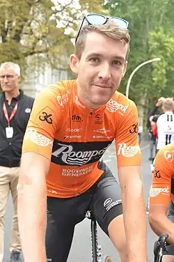 A male cyclist in partial uniform casually looking into the camera