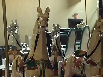 A close-up of several white carousel horses on a historic carousel