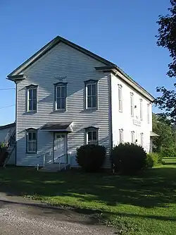 A white two-story clapboard building with green trim