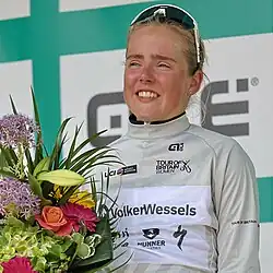 Eline Jansen wearing a white cycling jersey and holding flowers