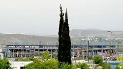 photo of stadium from outside with mountains in distance and trees in foreground