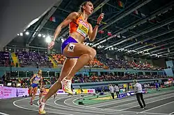 Photo of two sprinting athletes, Femke Bol in focus in the front and Viivi Lehikoinen out of focus in the background