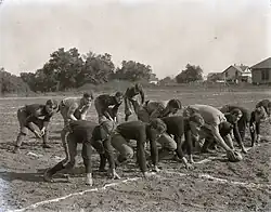 An American football team preparing for a snap on a dirt field