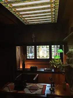 A desk in Wright's office. There are green and gold skylights on the ceiling.