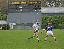 Scoreboard at a camogie game. The Garda Síochana team lead the Defence Forces by 3-8 to 2-8 (i.e., 17 to 14).