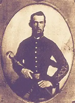 Blurry, sepia toned photo shows a man in dark uniform holding a weapon.