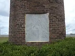 A brick pedestal with a stone plaque which reads: “This monument to the peanut, Turner County's most important agricultural product, is dedicated to the memory of Nora Lawrence Smith, December 25, 1886 - July 17, 1971. Member, Georgia Journalism's Hall of Fame, Editor and Co-Publisher of the Wiregrass Farmer, Turner County's Award Winning Newspaper and an untiring supporter of Turner County and its agricultural economy."