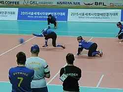The moment after a Sweden player throws the ball, his arm is still extended as the ball crosses the high ball line. Behind him, a defender is ready on hands and knees to intercept a return ball.