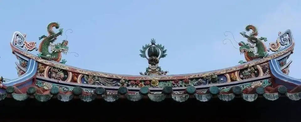 The ornate rooftop ridge of the temple is decorated with twin dragons and floral motifs.