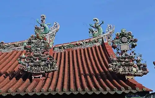 Roof top view showcasing detailed ceramic figurines and mythological elements atop the ridged tiles of the main temple structure.