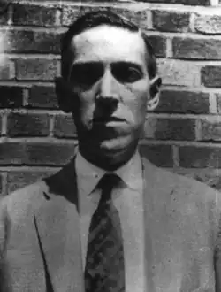 H. P. Lovecraft in front of a brick wall in Brooklyn