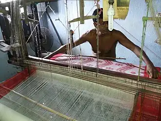 This weaver is weaving a piece of cloth about as wide as he can span. Hooghly district, West Bengal.