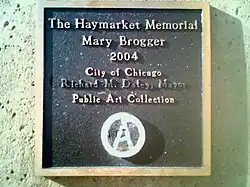 The marker under the Mary Brogger monument, vandalized with a circle-A