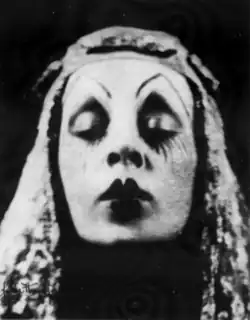A woman's face, with extreme stage makeup, eyes closed