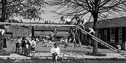 Playing children; some are using a climbing frame, others are on a field.