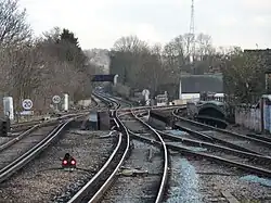 A pair of third-rail railway tracks are intersected by a second pair of tracks coming in from the right