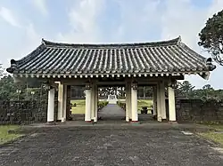 A gateway of four pillars creating three entrances covered by a traditional-style Korean roof