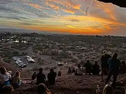 A group of people watch the sunset at Hole-in-the-Rock.