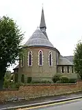 Holy Trinity Church, Lyonsdown Road, New Barnet, London, 1865 by Ewan Christian, showing the strong chancel apse in stock brick with red brick banding[159]