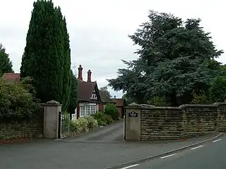 Lodge, among trees, at the entrance to a country house