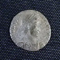 A smaller silver coin in the centre a head – still a fairly round coin but the inscription is not intact and there is no space between it and the rim