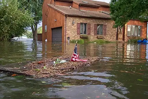 A building partially submerged in water with an object with the American flag in the foreground.