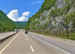 A stretch of highway, with a fence along the side to keep rocks out of the road