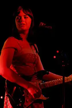 Colour photograph of Isa Maria performing live in 2007. She is playing underneath a red light, making her appear red.