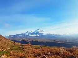 Snow‑dusted volcanic cone with rugged slopes under a clear blue sky