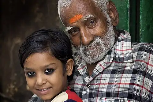 A Varanasi food seller with his granddaughter wearing kajal