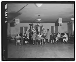 Eight women sitting in a row with two additional women standing with large American flags