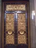 Bronze doors, designed by Cockerell, 12 feet (4 m) 8 inches (20 cm) high by 6 feet (2 m) 4 inches (10 cm) wide and weighs 74 cwt, there are three on each side of the hall, also three similar doors at the south end lead to the Crown Court and a smaller one is beneath the organ.