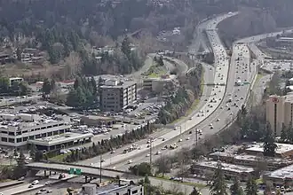 Aerial photograph of a freeway with light traffic passing through a built-up area with car dealerships and office parks