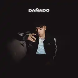 Cover art for Dañado, which depicts Iván Cornejo, wearing a black-and-white bomber jacket and a neck chain, drinking a glass of wine whilst sitting in a chair. Slightly-blurred text appears on the upper center as 'Dañado', in all capital letters.
