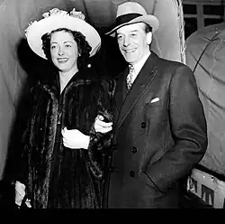 man in smart daytime clothes with younger white woman in a fur coat