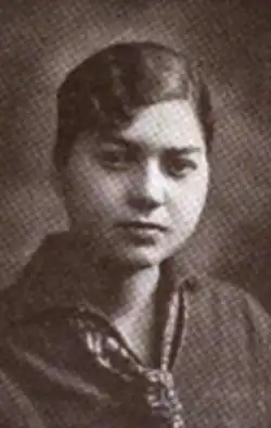 A young light-skinned Black woman, hair dressed with a side part, wearing a print scarf and a dark top