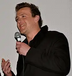 A man holds a microphone as he speaks