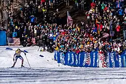 Jessie Diggins skis uphill before a crowd of onlookers.