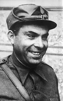 Portrait photograph of Buenaventura Durruti, smiling, while wearing a militia cap