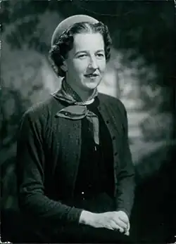 Portrait of a woman in black and white, wearing a suit and skirt, circa 1950s.