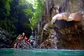 A man attempting to jump from a mushroom-shaped rock in Green Canyon Indonesia