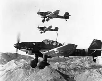 a black and white photograph of seven aircraft in flight over a smoky battleground