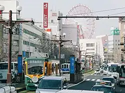 Kajiyachō Tram Stop with its back to the Kagoshima-Chūō Station Building having Ferris wheel