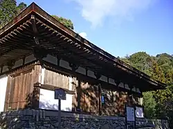 Wooden building on a stone platform with white walls.
