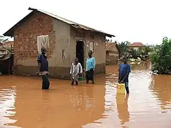 Boys standing in flood waters in residential area, Kampala, Uganda