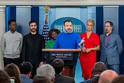 During COVID-19 and the streaming wars, multiple TV shows and films released on internet streaming services instead of theaters. Squid Game was a global success as a result of the streaming wars that began in the early 2020s, involving many new streaming services. Services such as Apple TV+, HBO Max, and Paramount+ were popular. Pictured above is the cast of Apple TV+'s Ted Lasso.